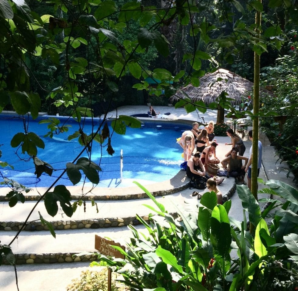 a group of people sitting next to a swimming pool.