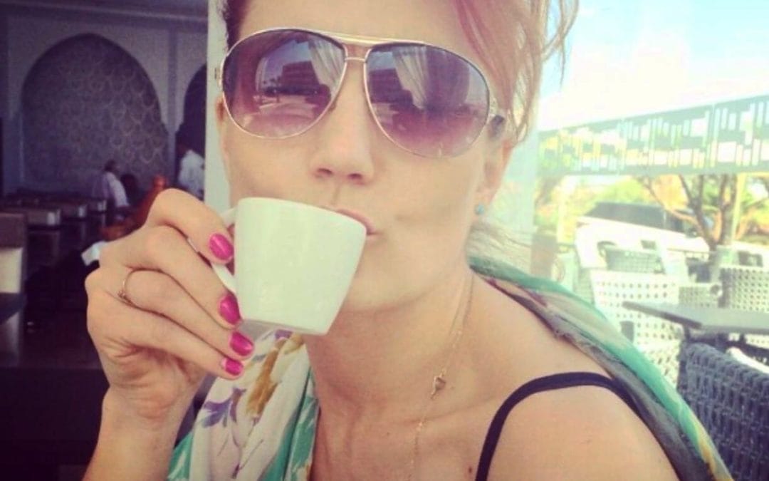a woman wearing sunglasses drinking a cup of coffee.