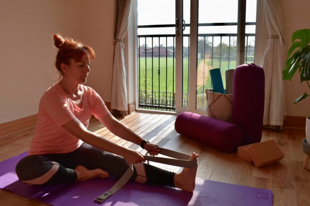 a woman sitting on a yoga mat with a pair of scissors.