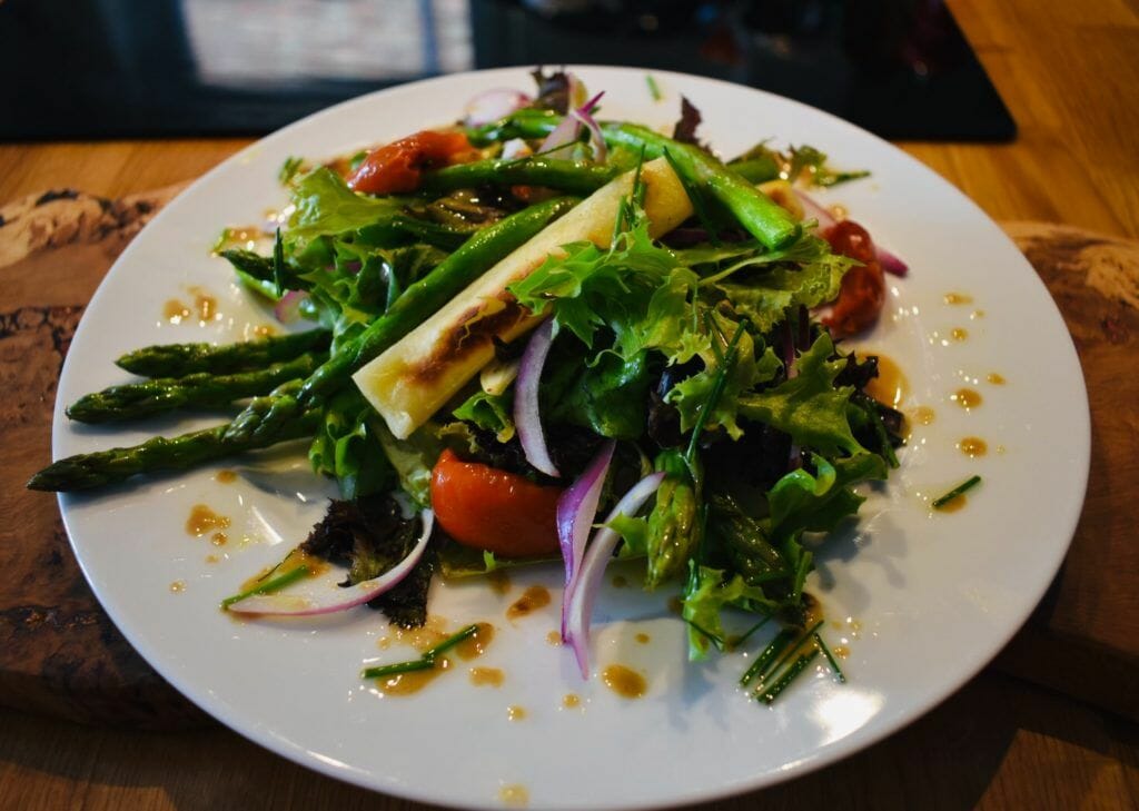 a white plate topped with a salad on top of a wooden table.