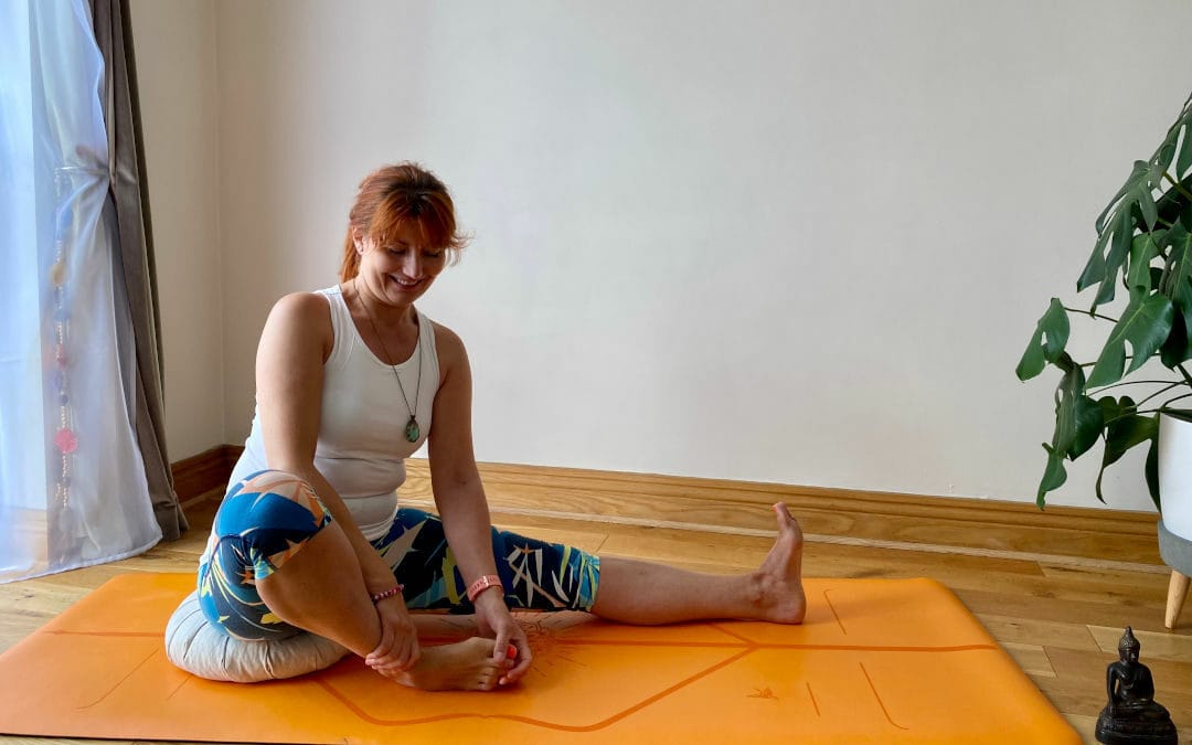 a woman sitting on a yoga mat in a room.