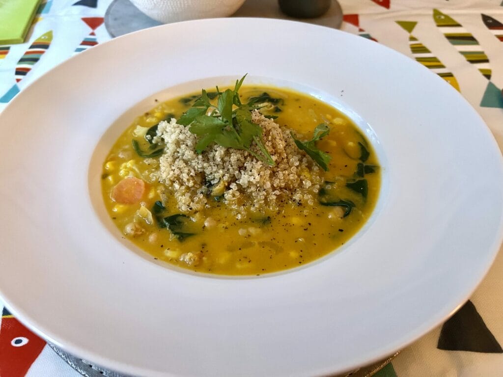 a white plate topped with a soup filled with vegetables.