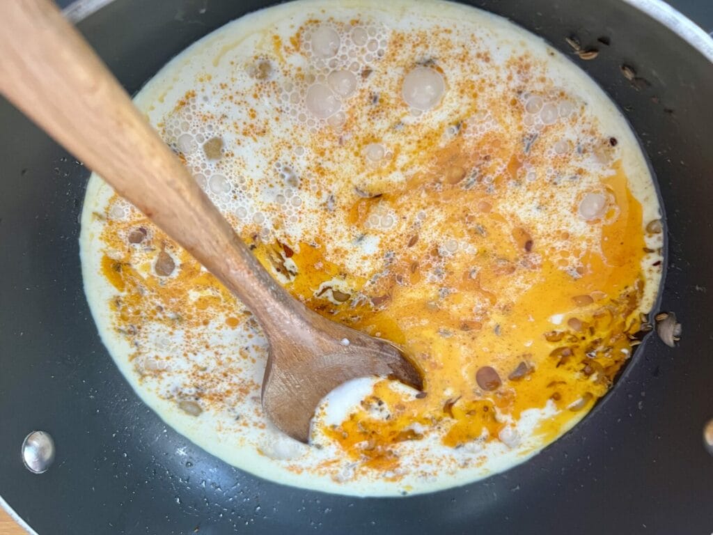 A Turmeric-Infused Butternut Squash Medley featuring eggs in a pan and a wooden spoon.